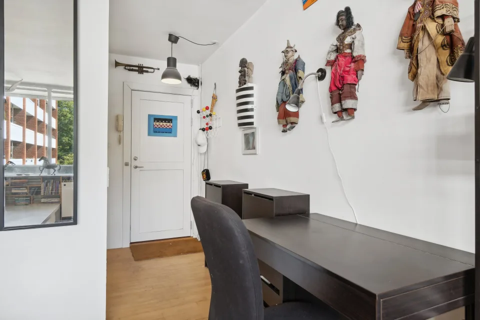 Entréen før renovering med skrivebord langs væggen og hoveddøren for enden.